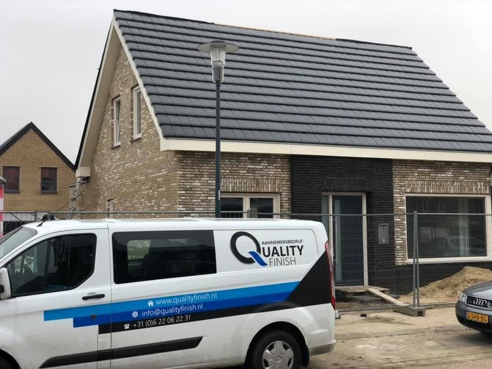 Nieuwe woning met een witte Quality Finish-bedrijfsbus met logo en contactgegevens ervoor