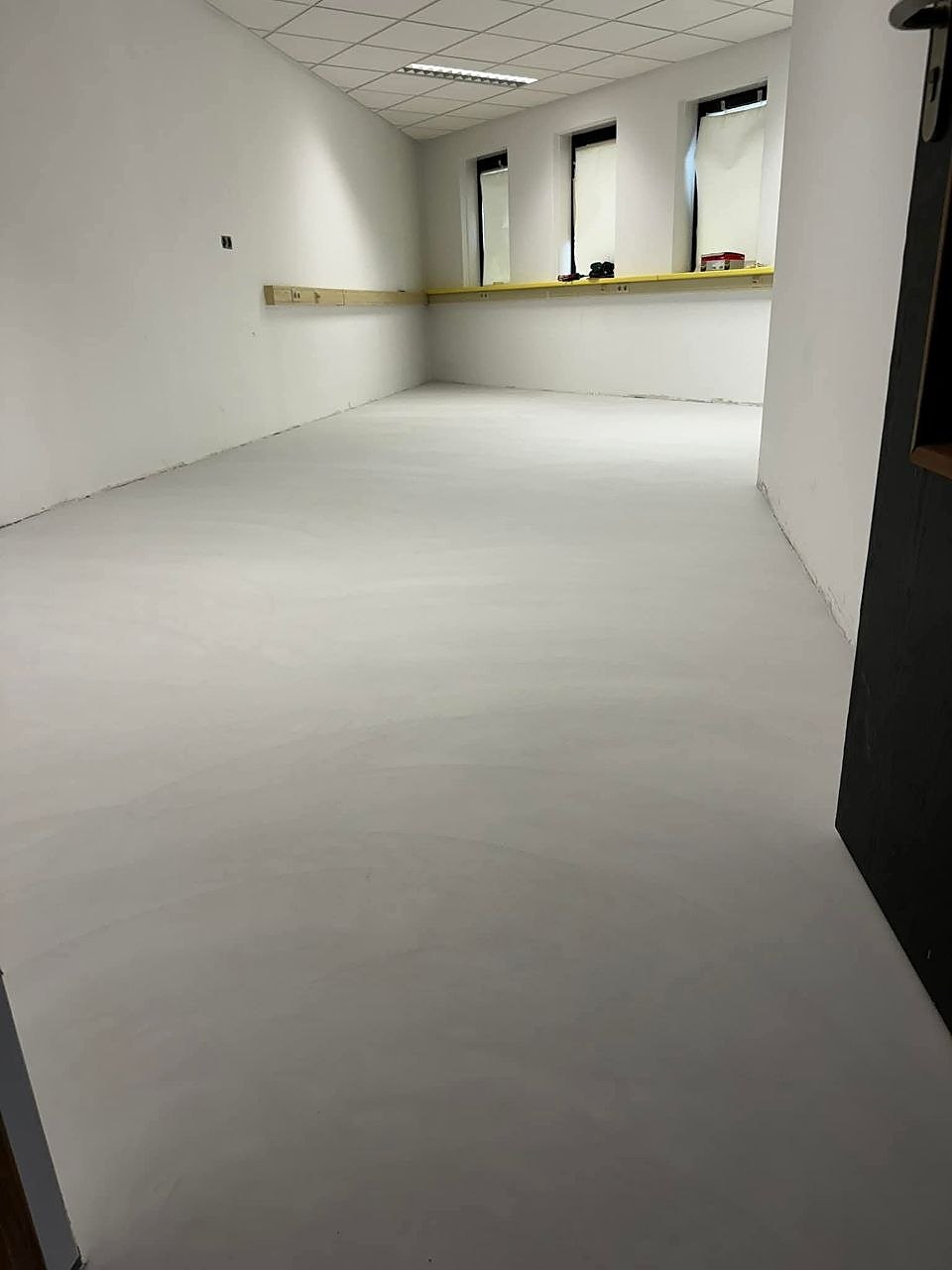 Lege ruimte met witte wanden en een egale grijze vloer na de afwerking