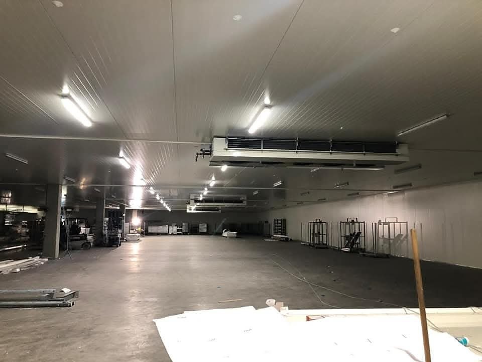 Grote koelruimte met witte wand- en plafondpanelen en verdampers aan het plafond