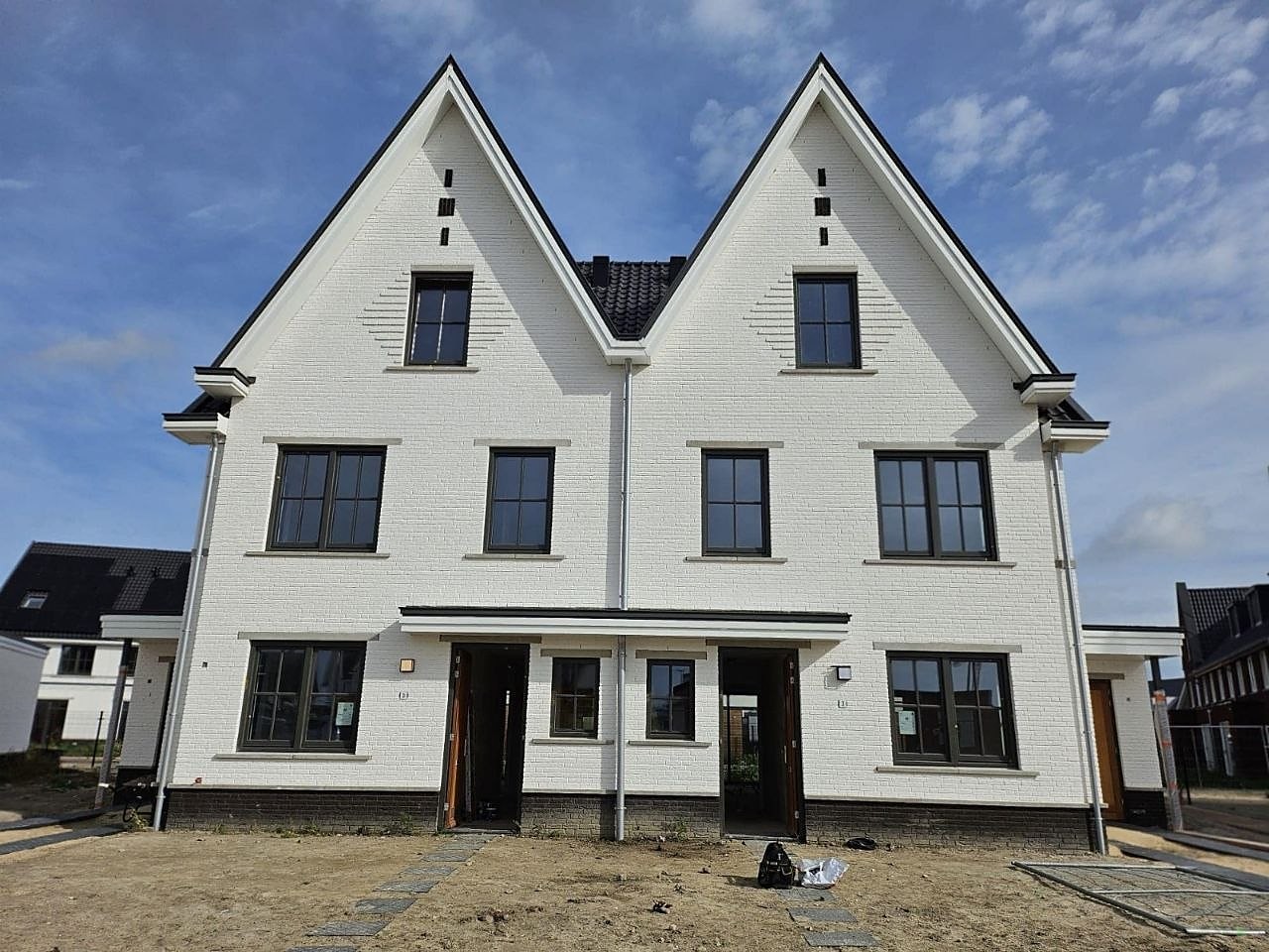 Witte twee-onder-een-kapwoning met twee puntgevels en donkere kozijnen