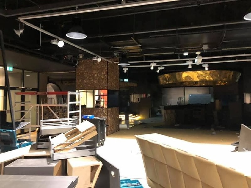 Interieur in afbouw met een bakstenen element, rolsteiger en materiaal op de vloer