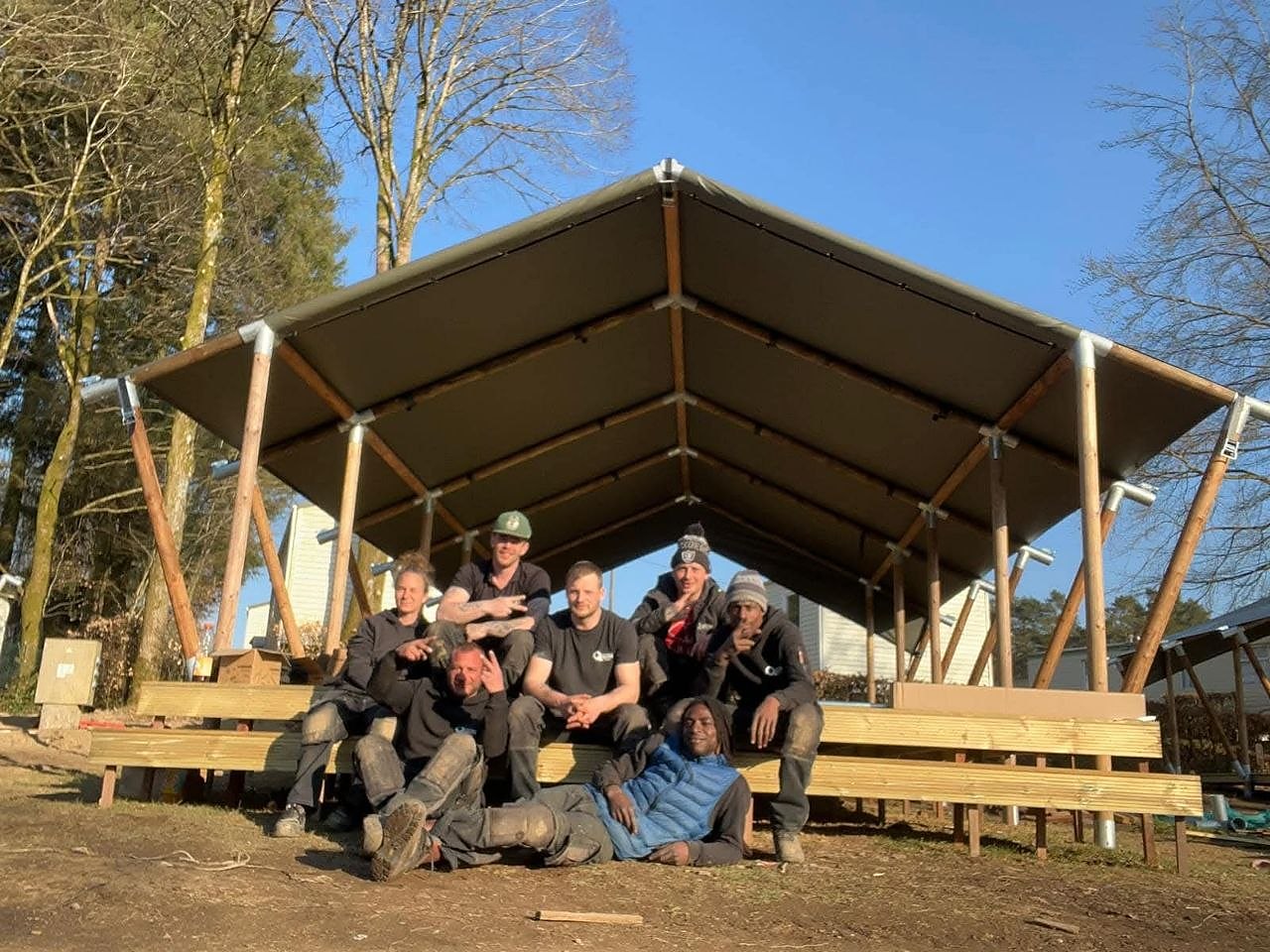 Medewerkers van Quality Finish op een vlonder onder een houten constructie met tentdoek