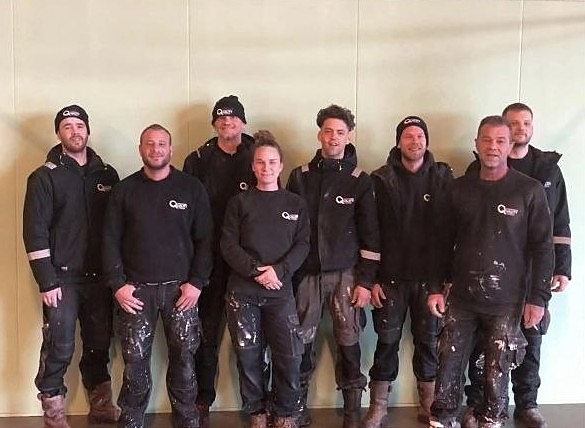 Het team van Quality Finish in werkkleding met het Quality Finish-logo